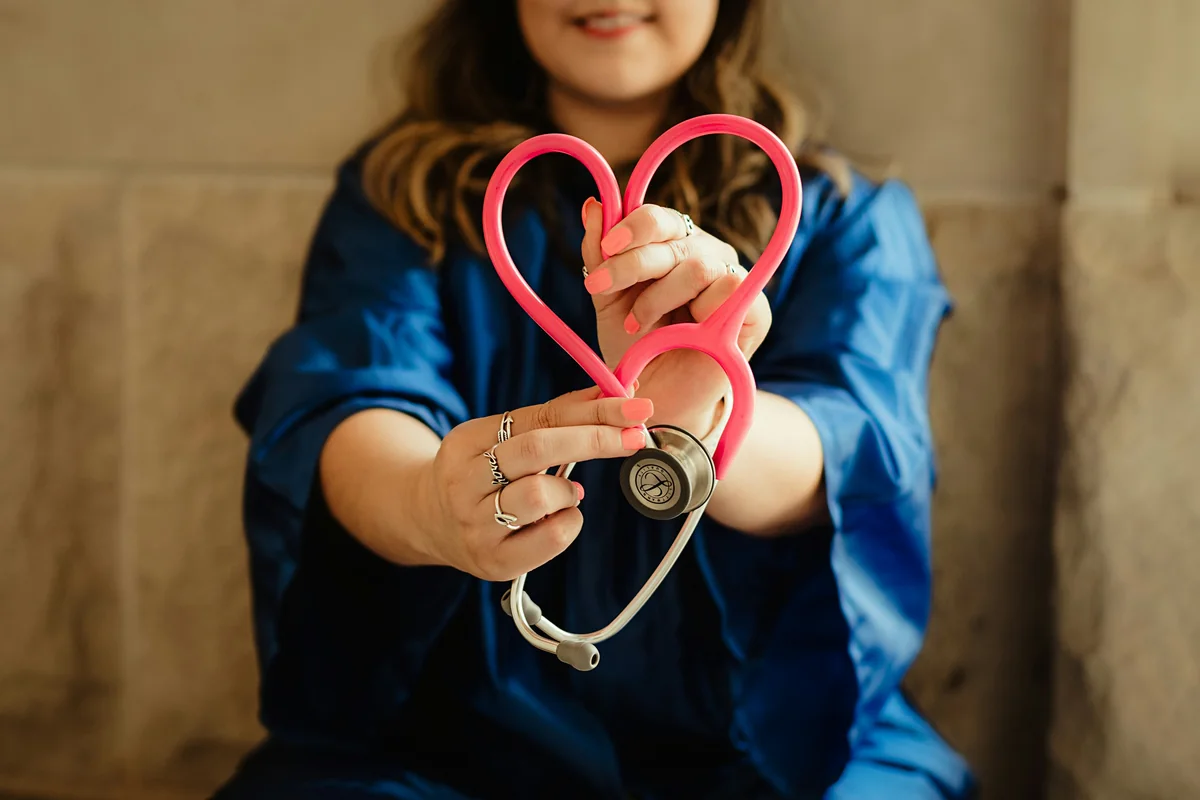 Healthcare professional holding a stethoscope in a heart shape