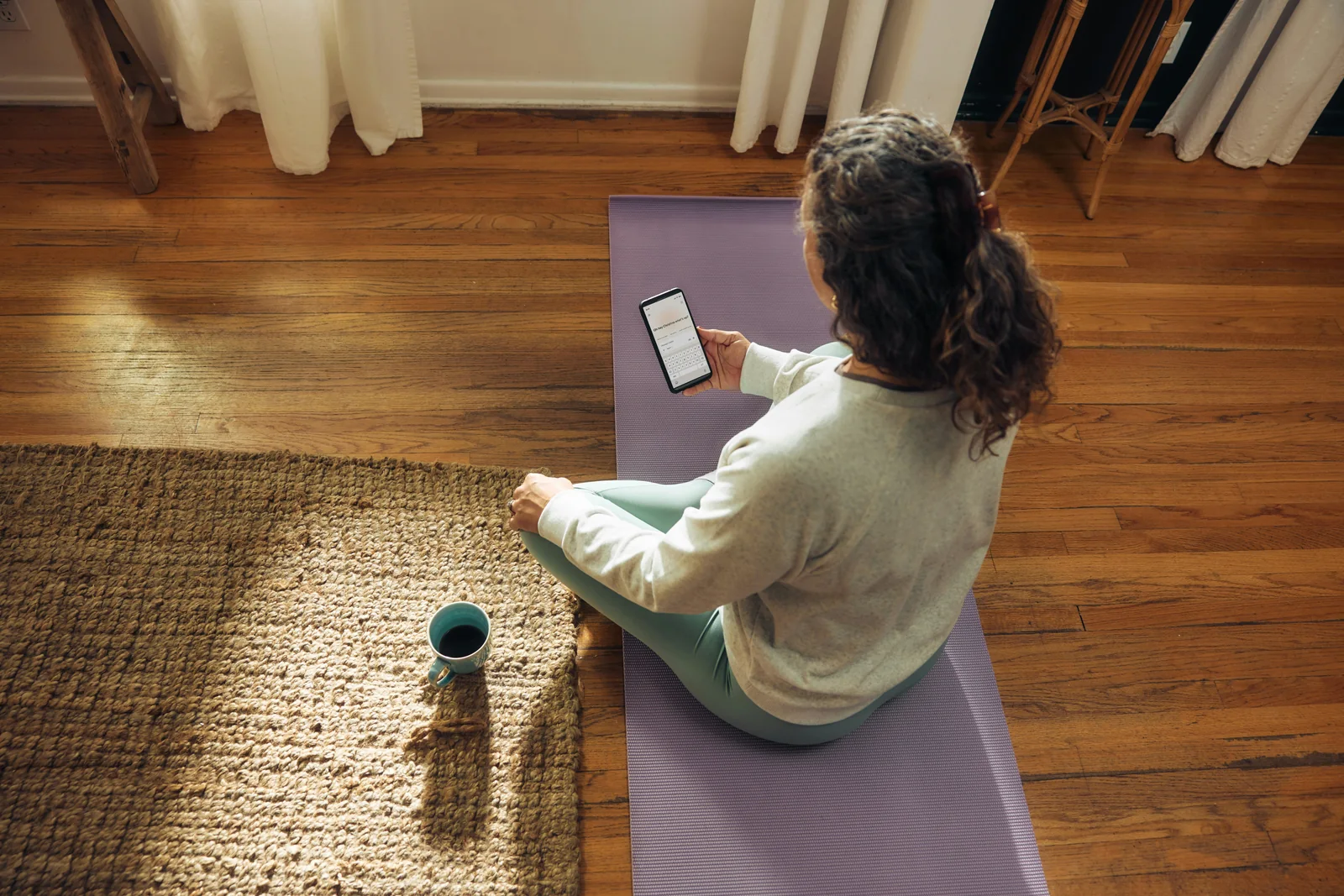A woman seated at home using her phone while taking a quiet pause
