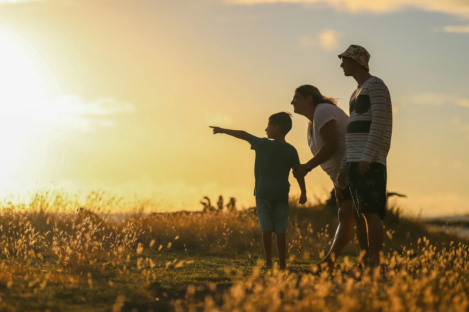 A multigenerational family standing together in warm evening light