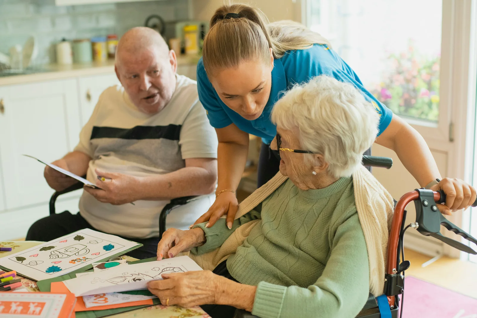 A caregiver helping two older adults enjoy a creative activity together