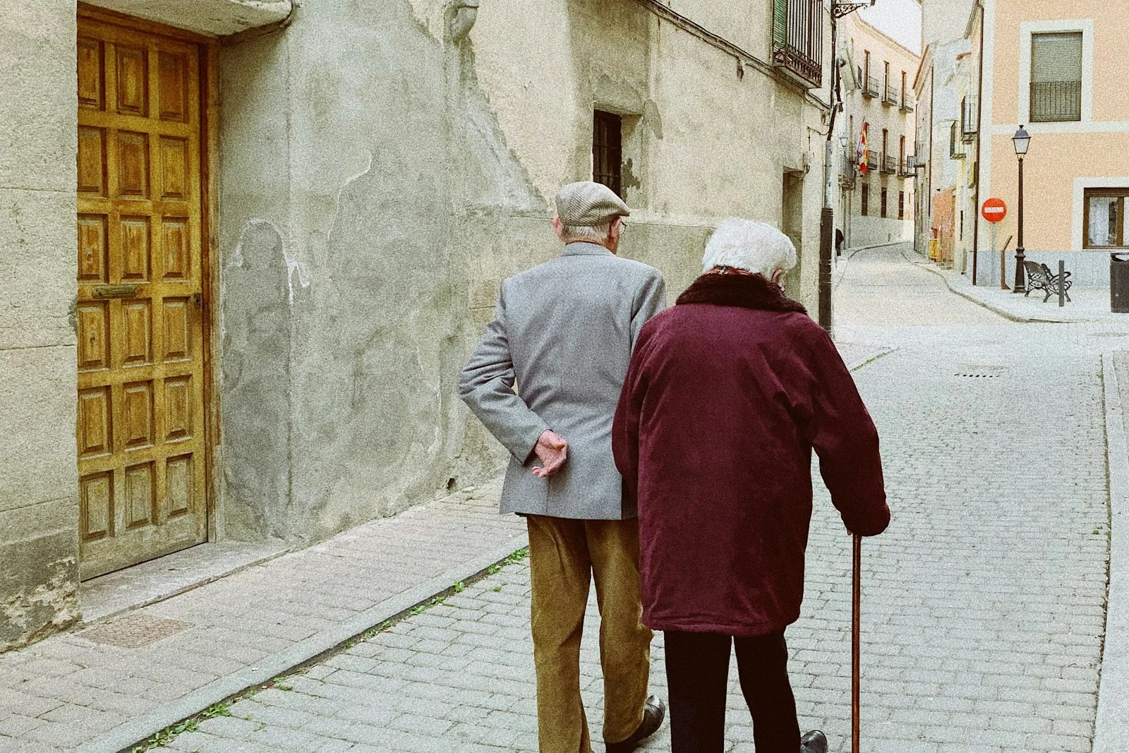 An older couple walking carefully together, one using a cane