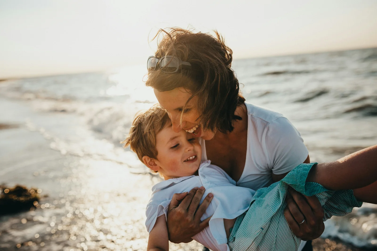 A parent holding a child close beside the ocean